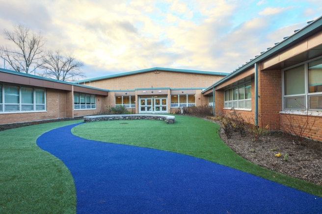 a courtyard area of an elementary school with a bright blue path to a seating area