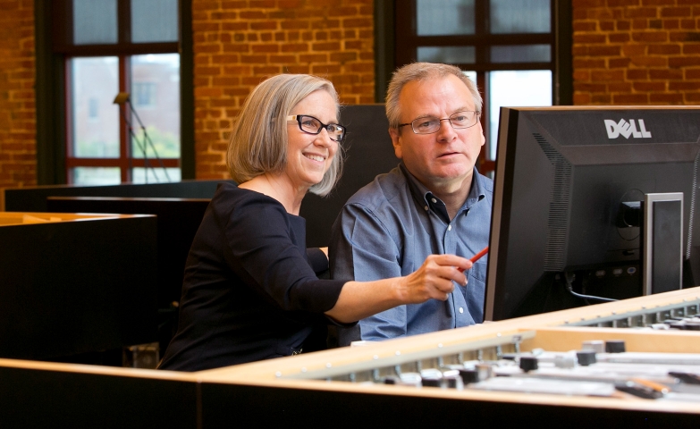 Two people working together on a shared computer.