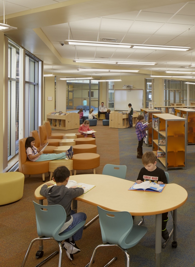 elementary age students reading and learning in a media center