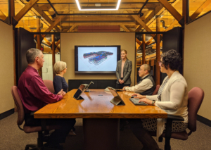 five people in a conference room looking at a monitor