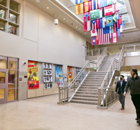 the lobby of the south high community school, which features a flag display under a skylights and artwork on the walls