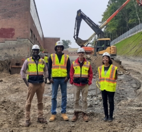 student interns and their advisors standing in front of a construction site in hard hats
