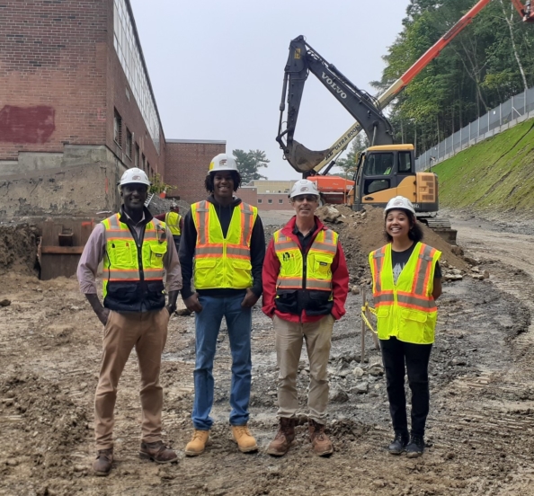 student interns and their advisors standing in front of a construction site in hard hats