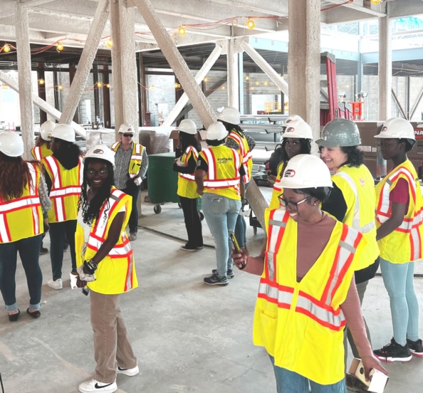 high school girls from the Eureka! program in hard hats tour construction site