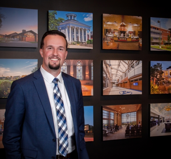 sean brennan in front of a wall with images of building projects
