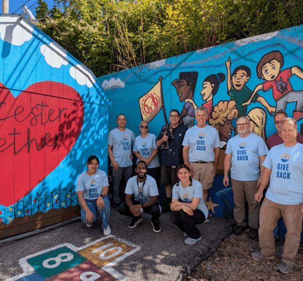 a group of people in matching Unisted Way shirts stand in front of a mural that says, Worcester Together