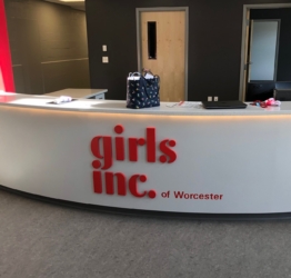 the girls inc logo is displayed on the front of their lobby desk