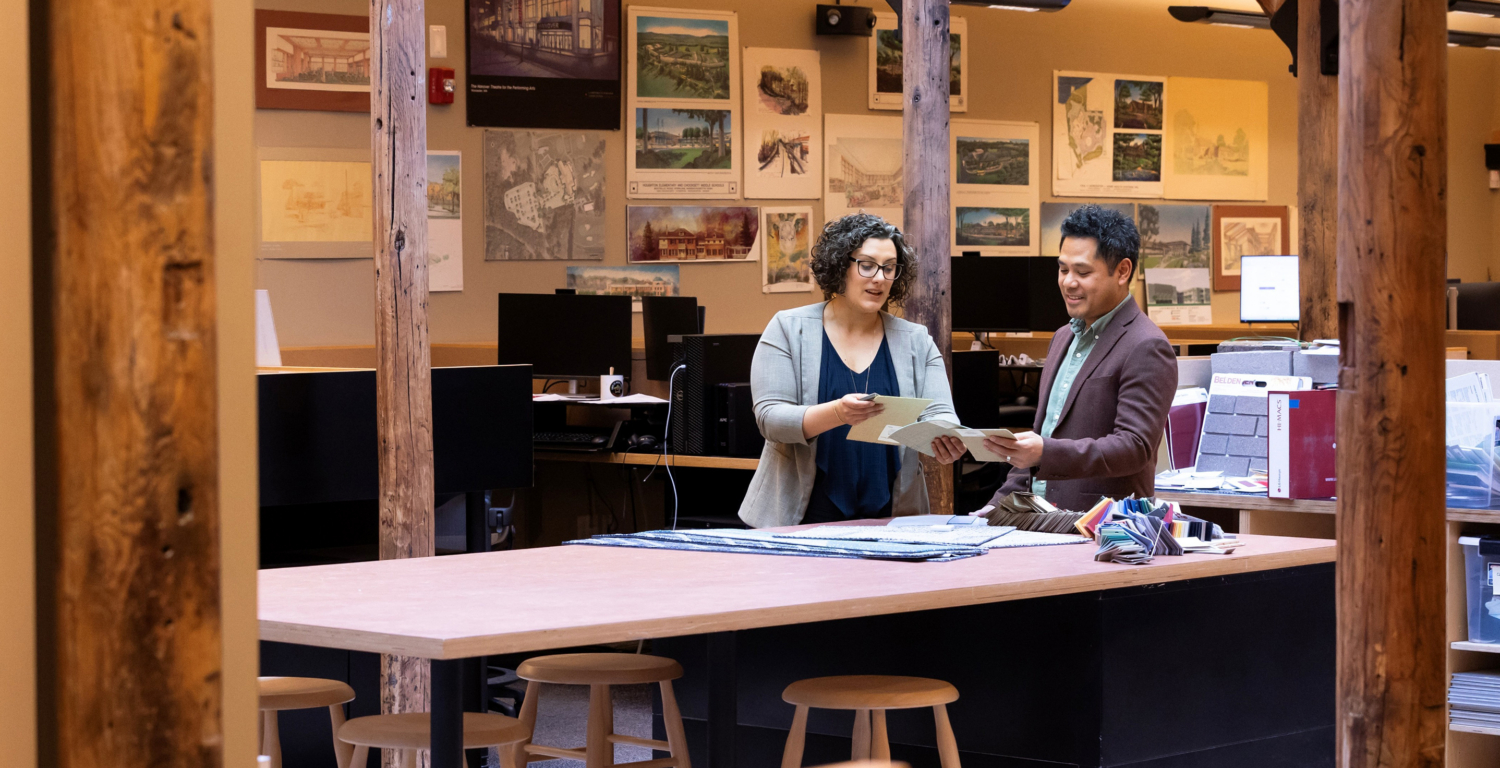 two people standing at a table in an architectural office