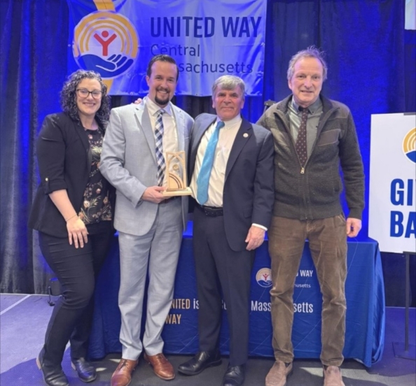 four people posed with award in front of a United Way banner