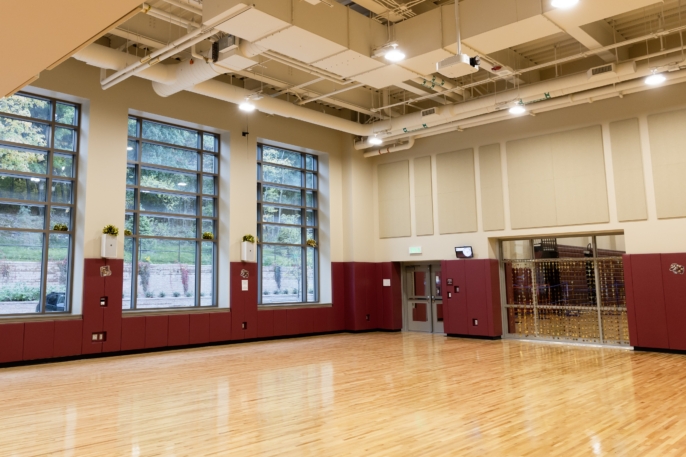 a gymnasium with tall windows along the back wall